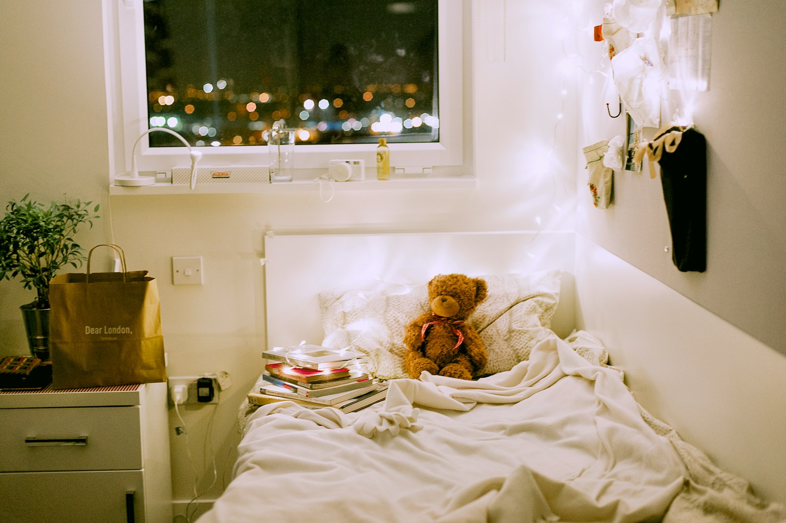Kuscheltier auf einem Kinderbett im warmen Abendlicht, draußen ist es Nacht